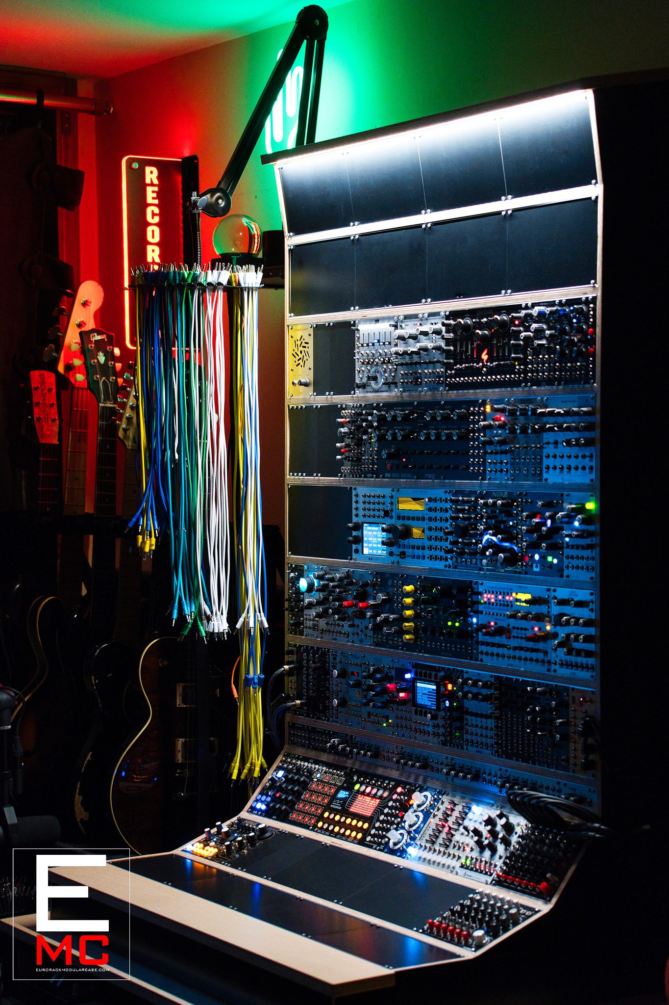 31U True North eurorack case | Fully populated and installed in Nate Lueck's studio alongside guitars and a neon Recording sign | EurorackModularCase