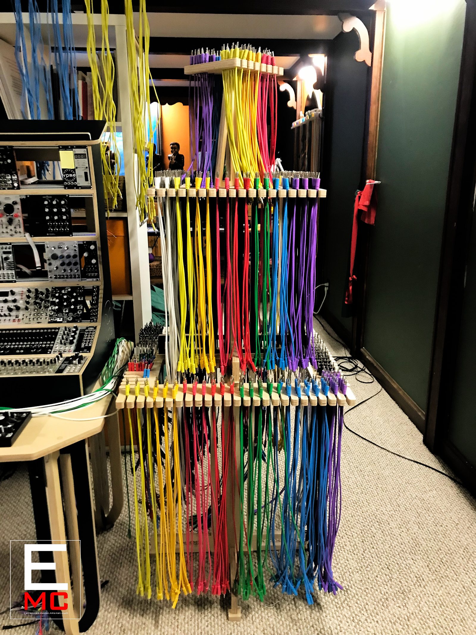Eurorack Cable Hanger | fully loaded with dozens of color-coded patch cables cascading from both tiers in a studio corner | EurorackModularCase