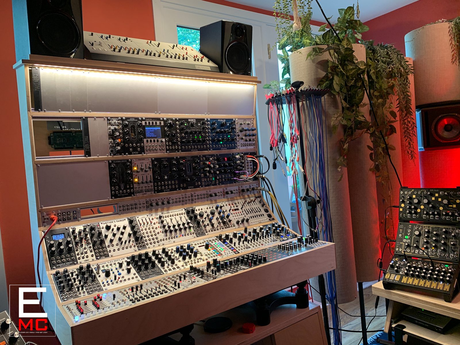 Alan Wilkis | Eurorack case loaded with modules in his red-walled studio surrounded by plants | Studio Egregia