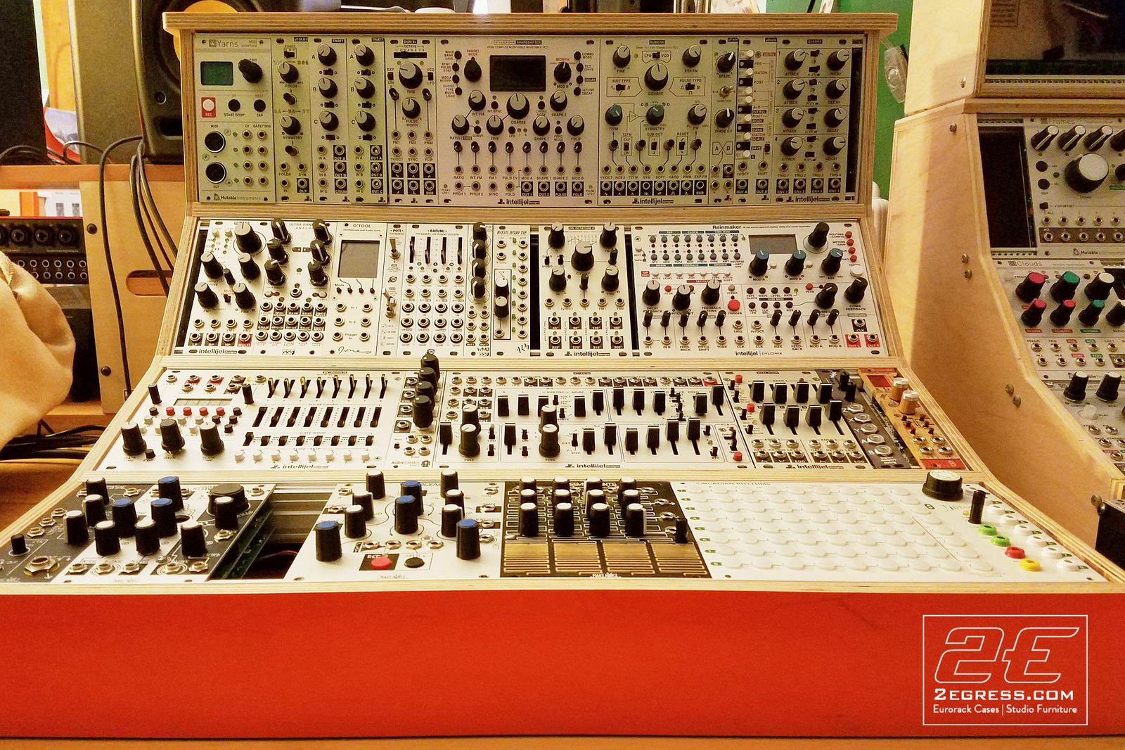 Andy Wegman | Close-up of the fully patched 12U eurorack case with its orange-red base panel | Studio Egregia