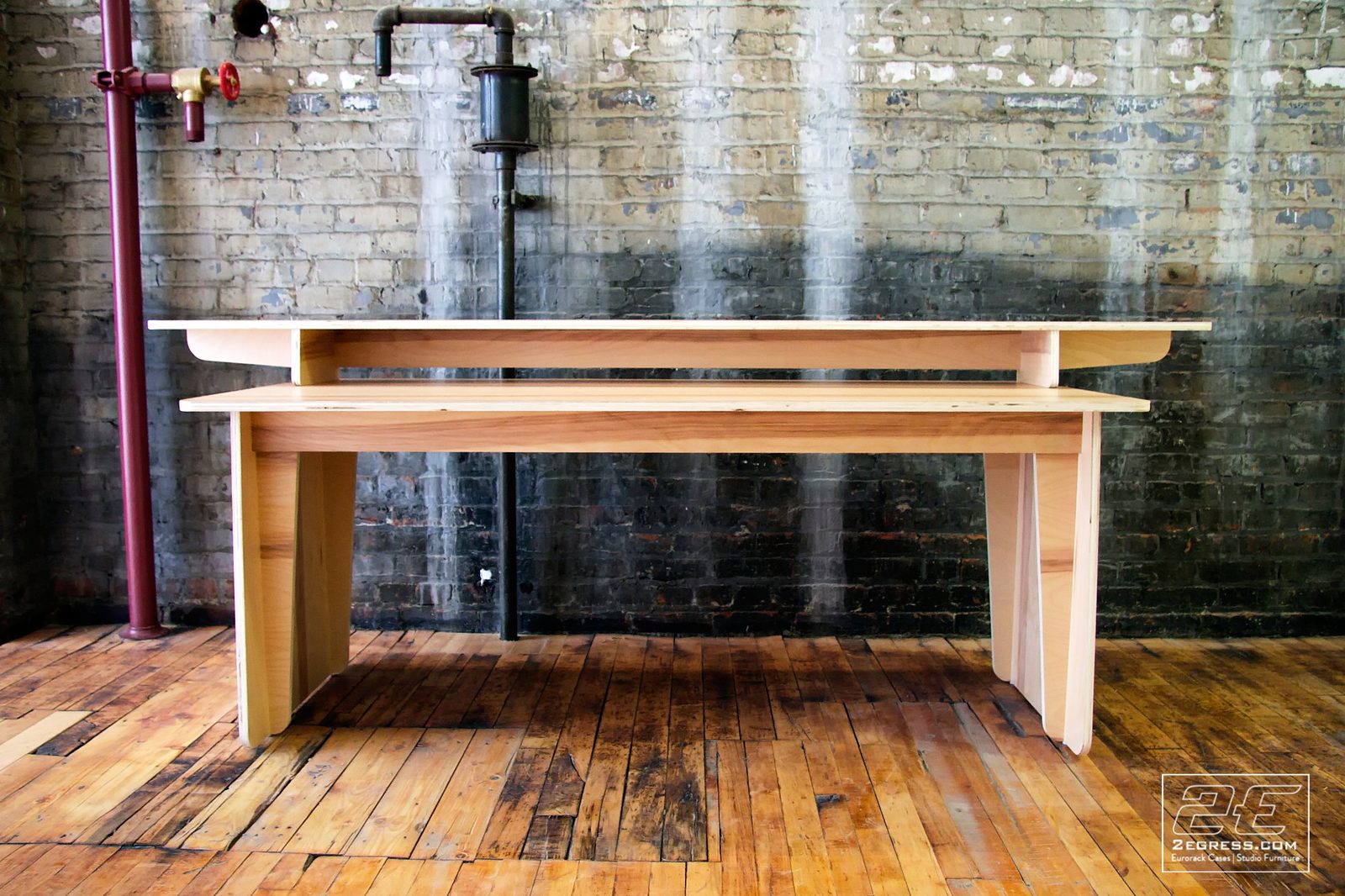 Catalina Coman | Front view of the light plywood video-editing desk against an exposed brick wall | Studio Egregia