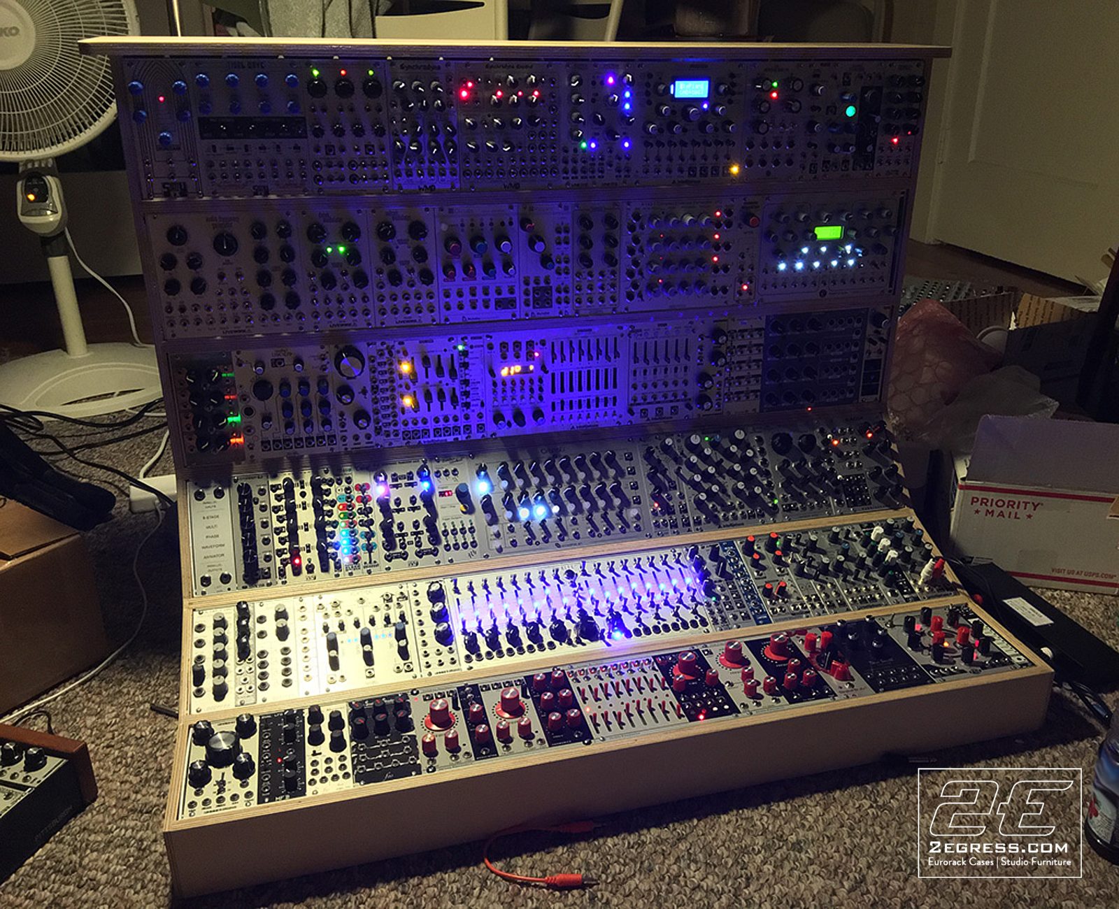 Charles Dworetz | The populated eurorack case lit from within by colorful module LEDs in a dim room | Studio Egregia