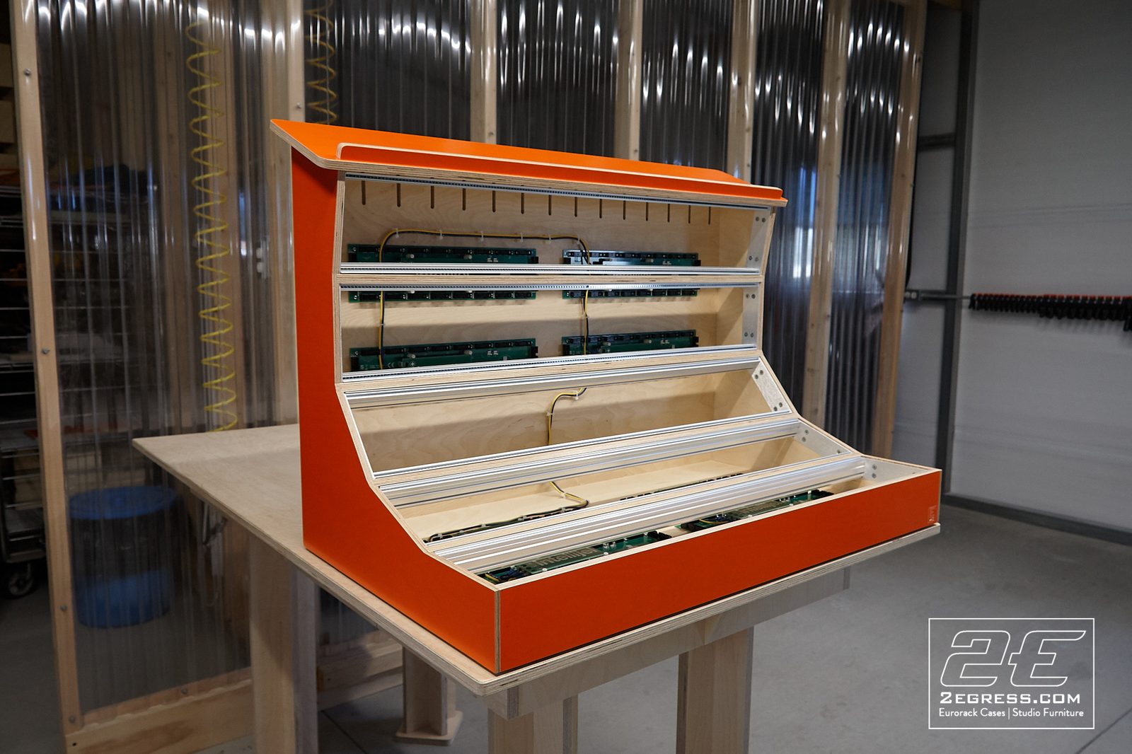 John Forester | Three-quarter view of the orange case on a workbench in the shop | Studio Egregia