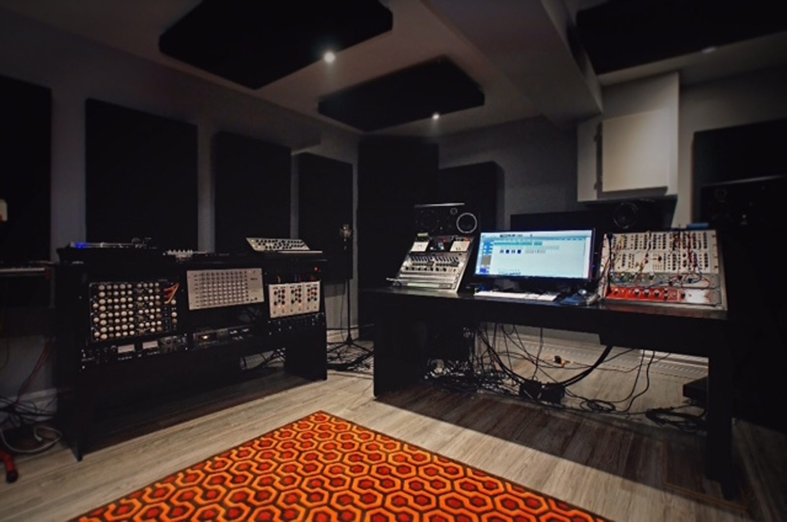 Paul Roussel | His Ontario studio with the black Raven desk and Sidewinder rack set up, dark room with an orange hexagon rug | Studio Egregia